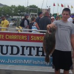 Teenage boy in grey shirt caught brown flounder on Judith M fishing boat