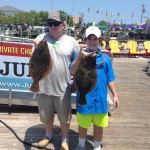 Older man and young boy holding two brown flounder in Ocean City Maryland