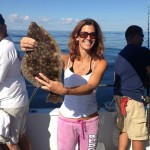 A woman displaying a brown flounder on the Judith M charter boat