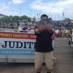 Man in black shirt displaying a fish in Ocean City Maryland