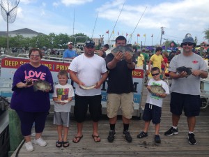 Family of six holding fish next to an Ocean city fishing boat