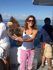 A woman displaying a brown flounder on the Judith M charter boat