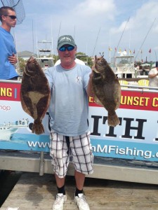 Man next to Judith M charter boat holding two flounder