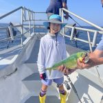 Boy holding fish on the dock of the boat