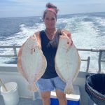 Picture of woman holding flounders on the deck.